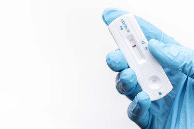 Midsection of doctor holding dental equipment against white background