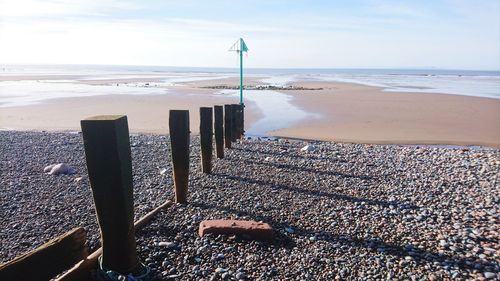 Wooden posts on beach against sky