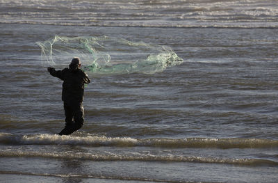 Rear view of fisherman fishing in sea