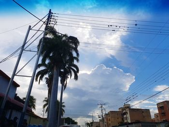 Low angle view of electricity pylon and buildings against sky