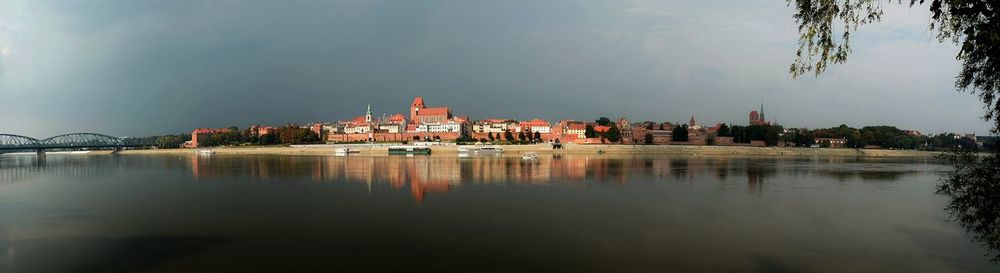 Buildings by lake against sky in city