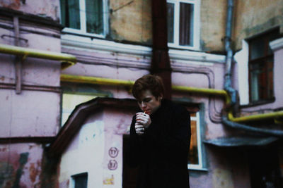 Man smoking cigarette against buildings