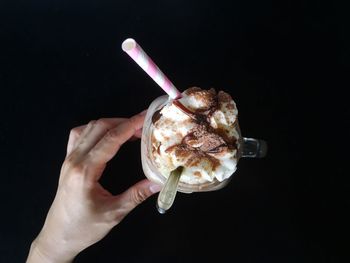 Cropped image of person touching ice cream against black background