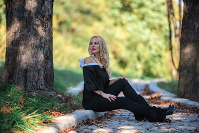 Young woman sitting on tree trunk in forest