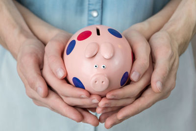 Close-up of people holding piggy bank