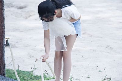 Girl washing legs with hose at beach