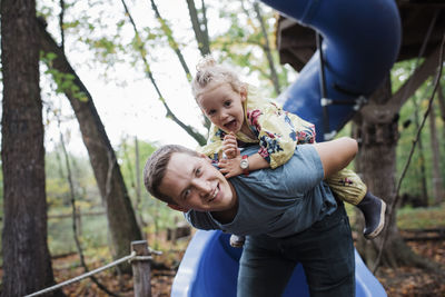 Portrait of father piggybacking daughter at playground