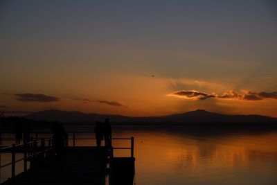 Silhouette people standing on mountain against sky during sunset