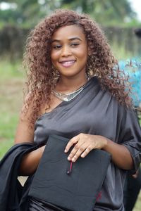 Smiling woman with mortarboard standing outdoors