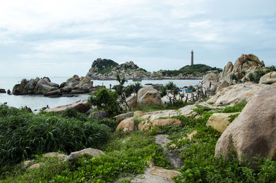 Scenic view of rocky shore against cloudy sky