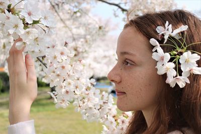 Close-up of young woman with cherry blossom tree
