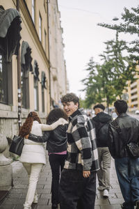 Side view portrait of smiling boy walking with teenage friends at street