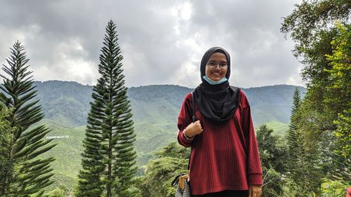 Portrait of smiling young lady standing on land against air cold sky