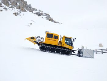 Yellow cart on snowy field against sky