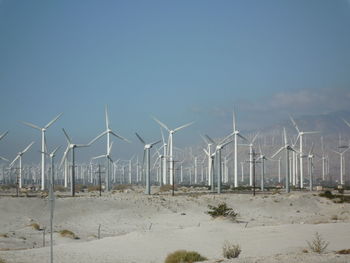 Wind turbines on field against sky