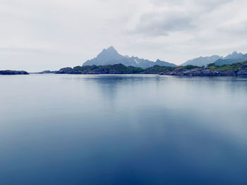 Scenic view of calm sea against sky and mountain