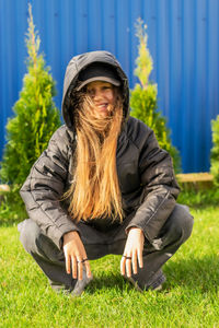 Portrait of young woman sitting on grassy field.