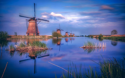 Traditional windmill by lake against sky
