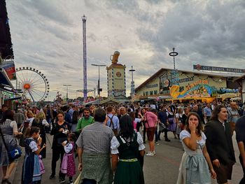 People in amusement park against sky in city