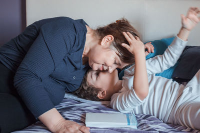 Grandson kissing grandmother on bed at home