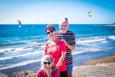 Portrait of friends enjoying at beach against sky