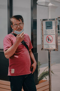 Portrait of man with arms raised standing against sign