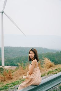 Portrait of woman sitting on landscape against sky