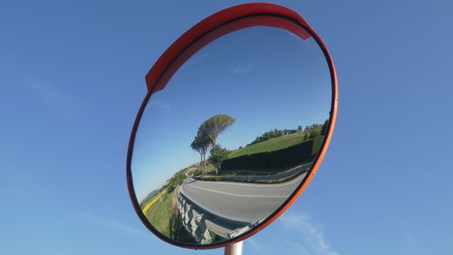 Low angle view of tree in road mirror against sky