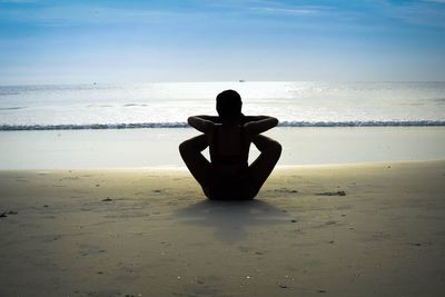 Woman sitting on beach against sea