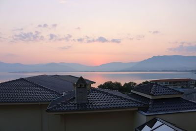 Houses by sea against sky during sunset