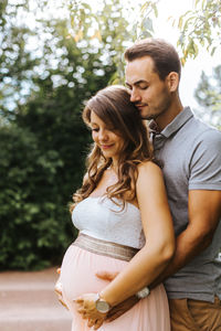 Husband embracing pregnant wife outdoors