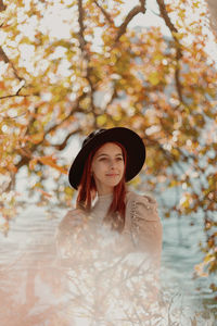 Portrait of young woman standing in park during autumn