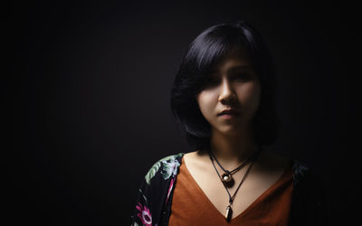 Portrait of woman against black background
