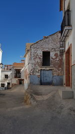 Street amidst buildings against clear blue sky