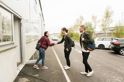 Woman shaking hands with coworkers outside industry in city