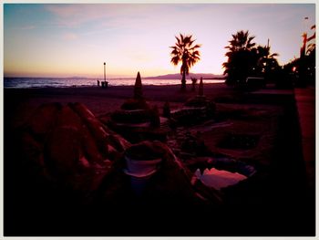 Silhouette palm trees on beach against sky during sunset