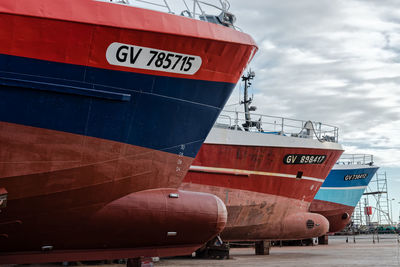 Ships moored at harbor against sky