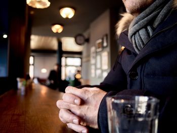 Midsection of man sitting at table in restaurant