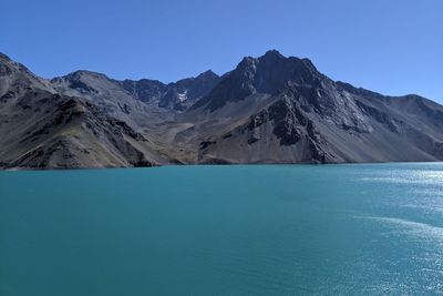 Scenic view of lake and mountains against clear blue sky