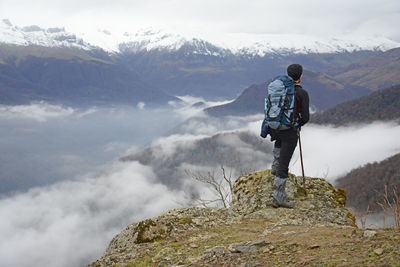 Rear view of man standing on rocks against mountain