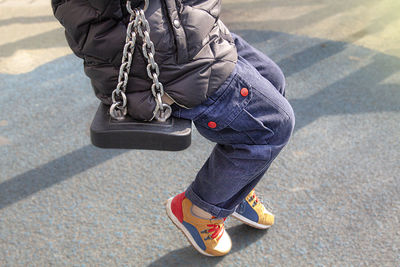 Low section of man swinging on playground