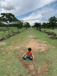High angle view of boy sitting on land against sky