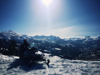 Man snowmobiling on snowcapped mountains against sky