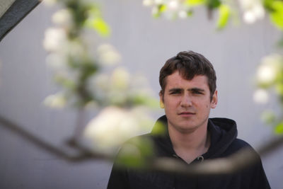 Portrait of young man standing against wall