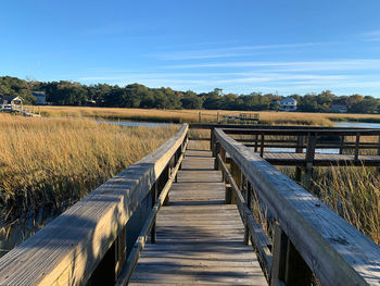 Boardwalk on field against sky