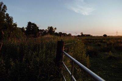 Fence on field against sky during sunset