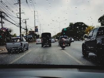 Cars on city street seen through wet glass window