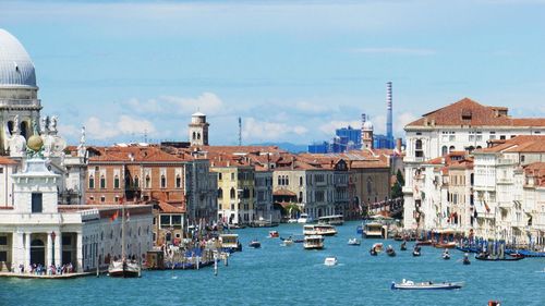 Boats in canal amidst buildings in city against sky