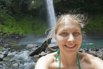 Portrait of smiling woman against waterfall