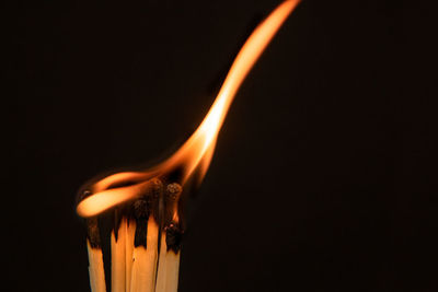 Close-up of burning candle against black background